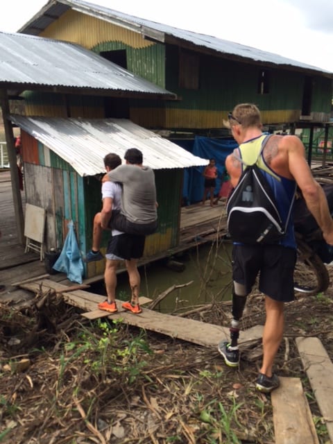 Joel carries Howie while Michael grabs his chair as they navigate the plank across Piranha infested waters of the Amazon